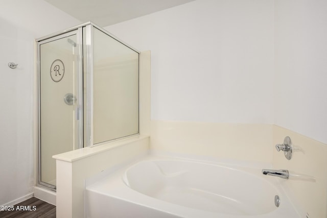 bathroom featuring a garden tub, a shower stall, and wood finished floors