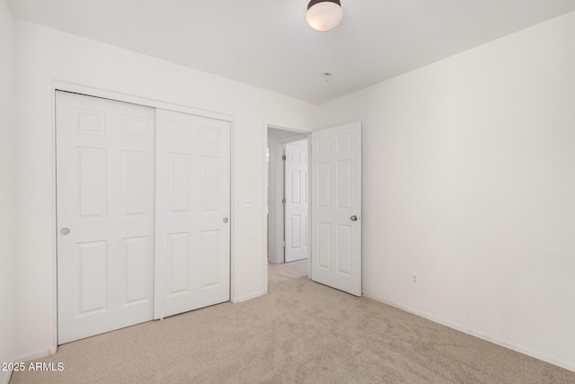 unfurnished bedroom featuring a closet, baseboards, and carpet flooring