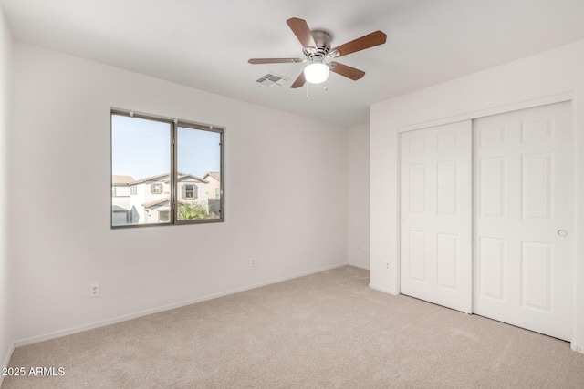 unfurnished bedroom with a closet, light colored carpet, visible vents, ceiling fan, and baseboards