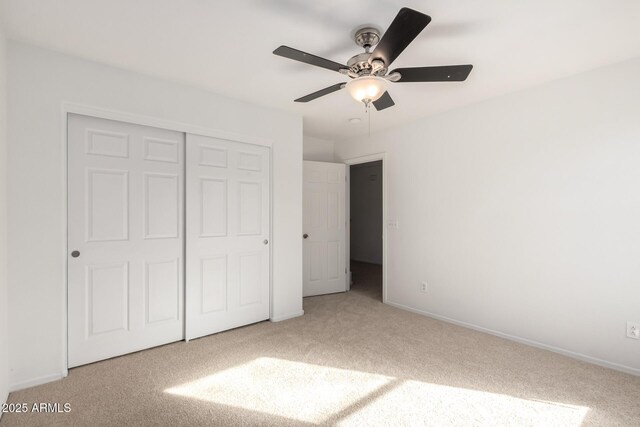 unfurnished bedroom with ceiling fan, a closet, baseboards, and carpet flooring
