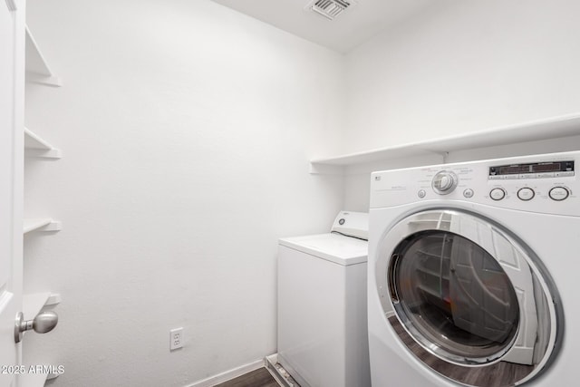 laundry room with washer and clothes dryer, visible vents, wood finished floors, laundry area, and baseboards