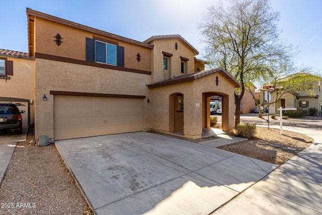 view of front facade featuring concrete driveway, a tile roof, an attached garage, and stucco siding