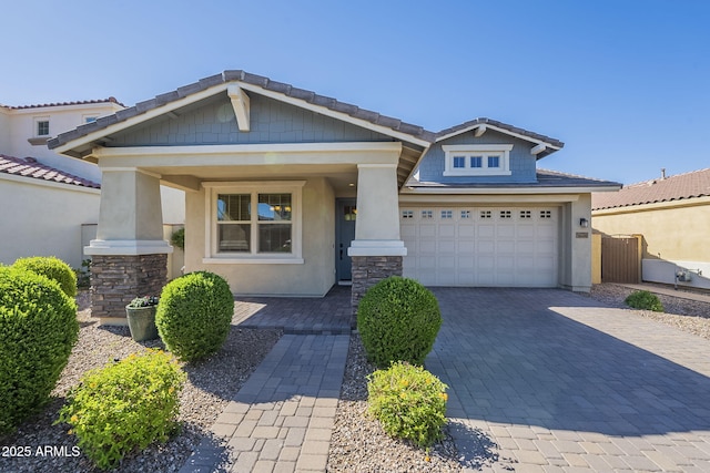 craftsman inspired home with decorative driveway, an attached garage, stucco siding, and a porch