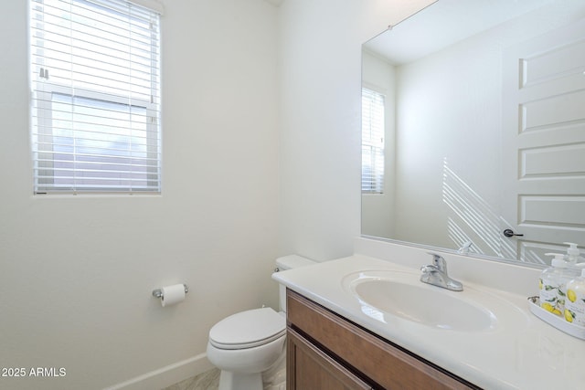 bathroom with toilet, baseboards, and vanity
