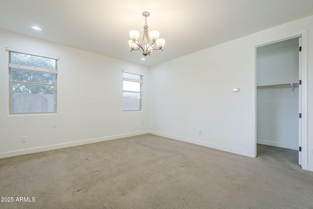 unfurnished bedroom featuring a chandelier, carpet, baseboards, a closet, and a spacious closet
