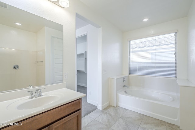 bathroom featuring a bath, vanity, a walk in closet, tile patterned floors, and recessed lighting