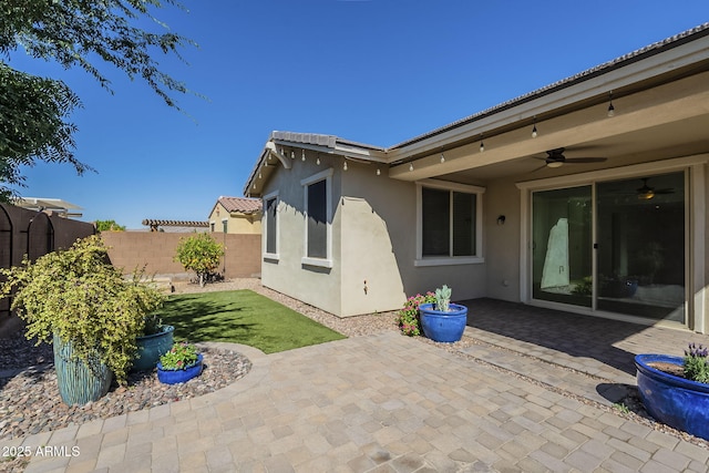 back of house with stucco siding, a patio area, fence, and a ceiling fan
