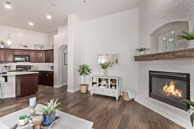 14864 W Riviera Dr, Surprise, AZ 85379 - living room with a brick fireplace, a towering ceiling, dark wood finished floors, and arched walkways