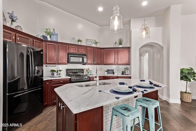 14864 W Riviera Dr, Surprise, AZ 85379 - kitchen with black appliances, arched walkways, dark wood-style floors, pendant lighting, and recessed lighting