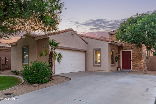 14864 W Riviera Dr, Surprise, AZ 85379 - mediterranean / spanish-style home with concrete driveway, an attached garage, stucco siding, a tiled roof, and stone siding