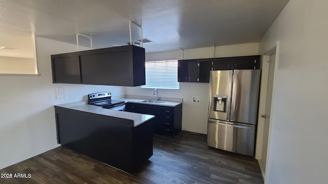 2908 N 53rd Ln, Phoenix, AZ 85031 - kitchen with stainless steel appliances, a sink, dark cabinetry, a peninsula, and dark wood finished floors