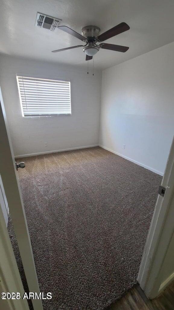 2908 N 53rd Ln, Phoenix, AZ 85031 - empty room with ceiling fan, dark colored carpet, and baseboards
