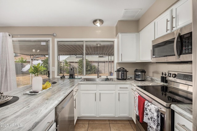 9028 W Osborn Rd, Phoenix, AZ 85037 - kitchen with stainless steel appliances, visible vents, a sink, light tile patterned flooring, and white cabinetry