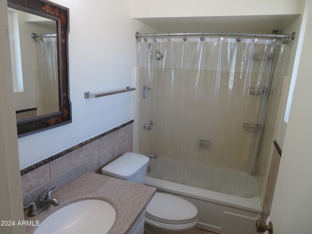 full bathroom with shower / bath combo, vanity, tile walls, and toilet