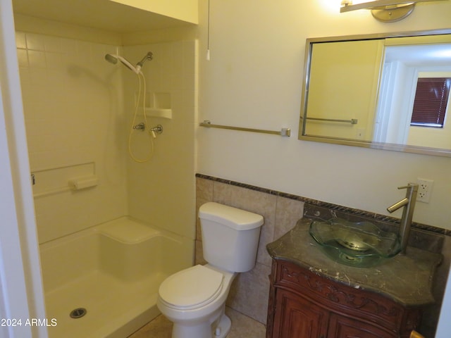 bathroom featuring a shower, toilet, vanity, and tile walls