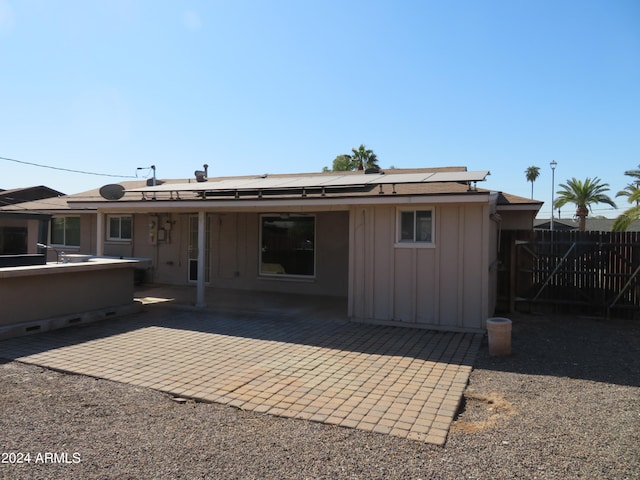 rear view of house with a patio area and solar panels