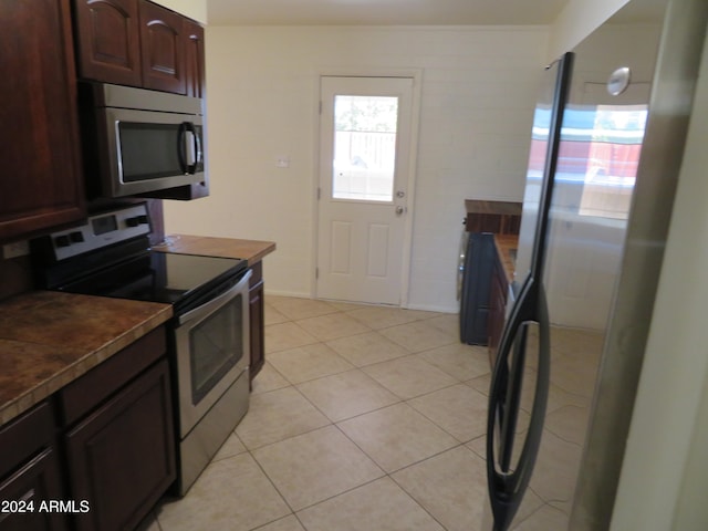 kitchen with light tile patterned floors, dark brown cabinetry, and stainless steel appliances