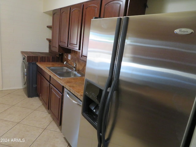 kitchen with appliances with stainless steel finishes, sink, and light tile patterned floors