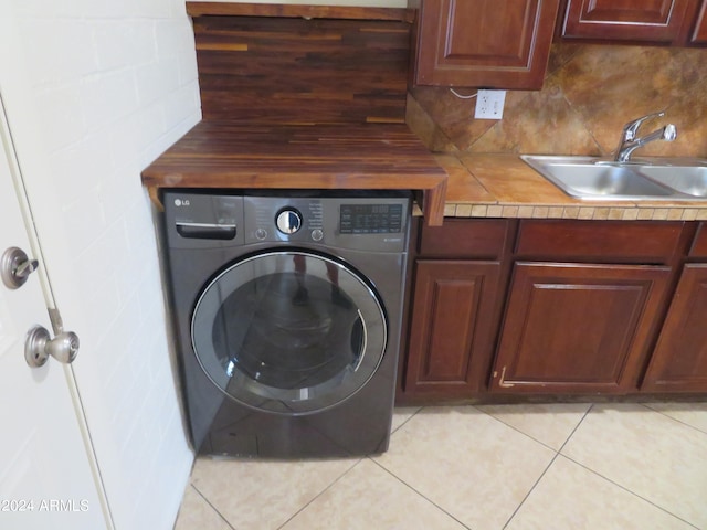 washroom featuring light tile patterned flooring, washer / dryer, sink, and cabinets