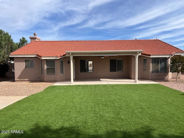 3876 Camino Del Vara, Sierra Vista, AZ 85650 - back of house featuring a tile roof, a chimney, stucco siding, a ceiling fan, and a lawn