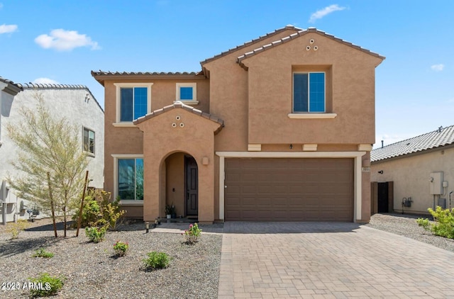 mediterranean / spanish-style house with a tile roof, decorative driveway, and stucco siding