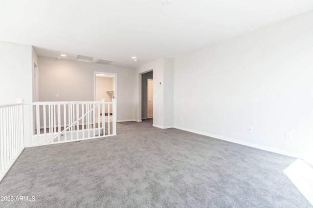 carpeted empty room with visible vents, attic access, and baseboards