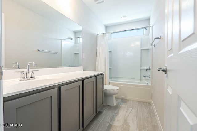 bathroom with vanity, wood finished floors, baseboards, shower / tub combo, and toilet