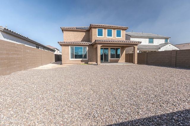 back of property featuring stucco siding, a patio, solar panels, and a fenced backyard