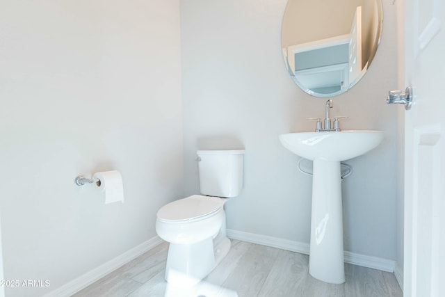 bathroom with baseboards, toilet, and wood finished floors