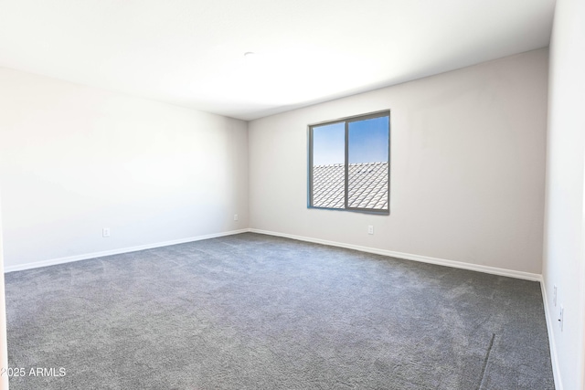 unfurnished room with baseboards and dark carpet