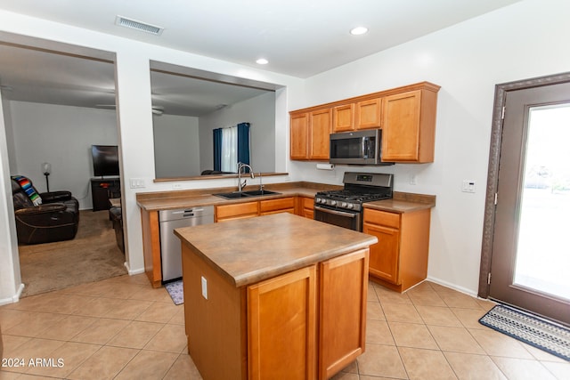 kitchen featuring a center island, a wealth of natural light, stainless steel appliances, sink, and light colored carpet