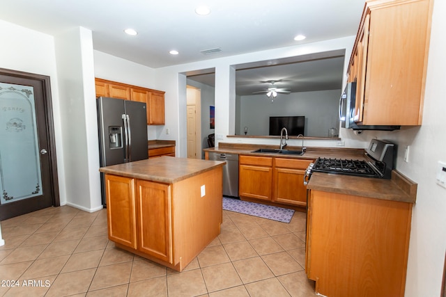 kitchen featuring a kitchen island, appliances with stainless steel finishes, ceiling fan, sink, and light tile floors