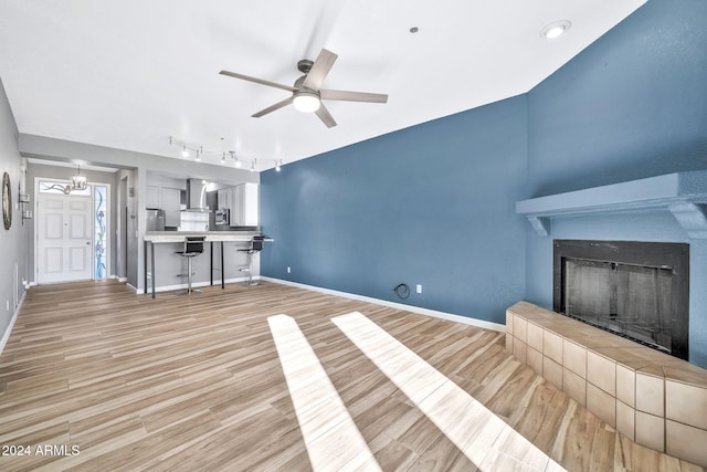 unfurnished living room featuring ceiling fan, light hardwood / wood-style floors, a fireplace, and track lighting