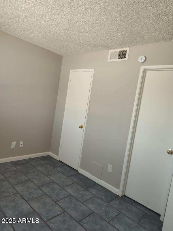 755 E Millett Ave, Mesa, AZ 85204 - empty room with a textured ceiling, baseboards, a smoke detector, and dark stone finish floors