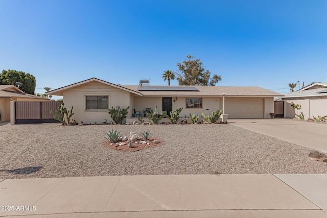 ranch-style house featuring roof mounted solar panels, driveway, an attached garage, and fence