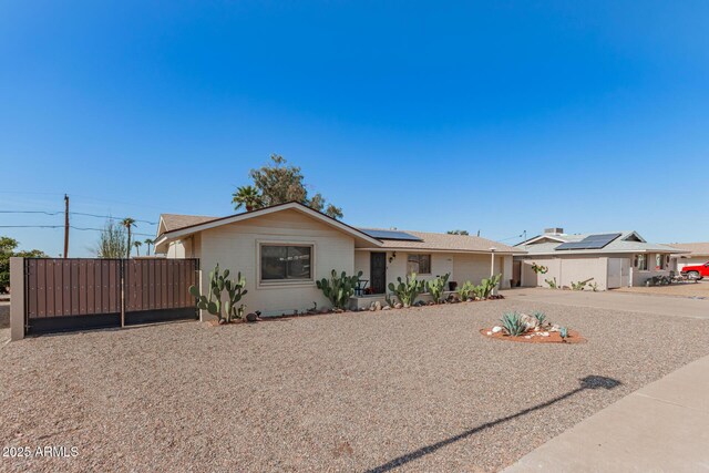 single story home featuring a gate, fence, and solar panels