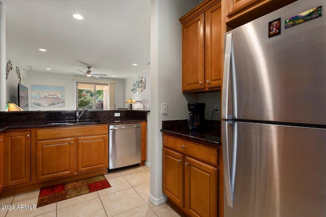 kitchen featuring dark stone countertops, light tile patterned floors, sink, and appliances with stainless steel finishes