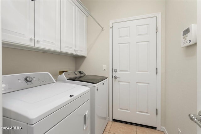 laundry area with cabinets, washer and clothes dryer, and light tile patterned flooring