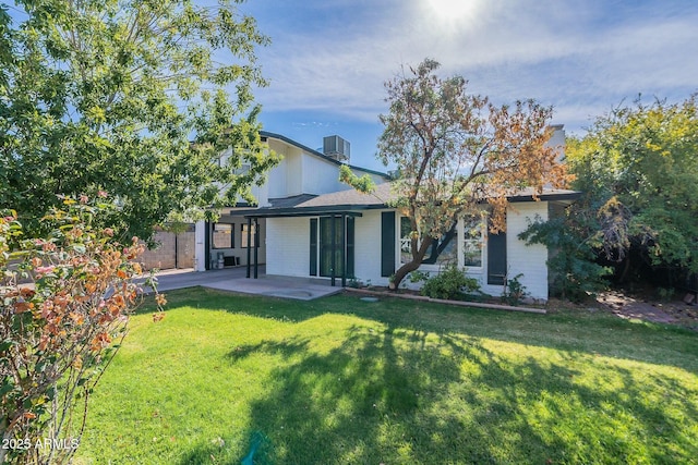 rear view of property featuring a patio area, central AC, a lawn, and brick siding