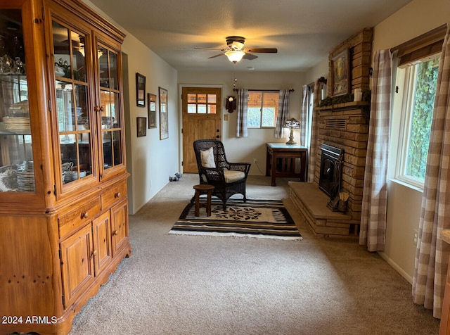 living area featuring ceiling fan, light colored carpet, and a wood stove