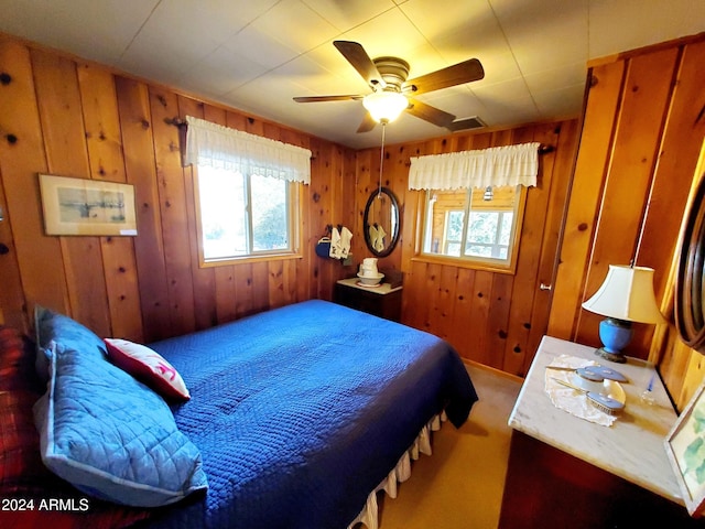 bedroom featuring ceiling fan and wooden walls