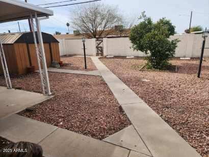 view of yard featuring a fenced backyard, an outdoor structure, and a storage shed