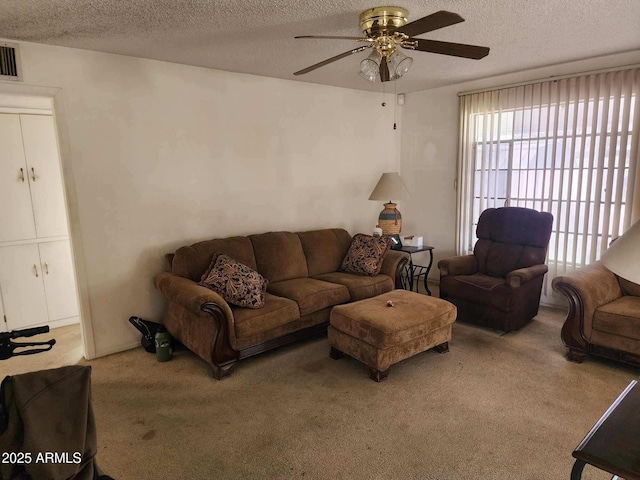 living room with a textured ceiling, carpet floors, and a ceiling fan