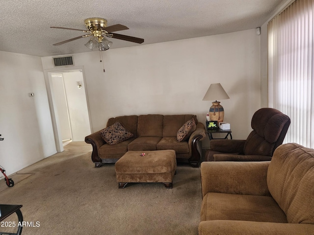 living area with carpet floors, visible vents, a textured ceiling, and a ceiling fan