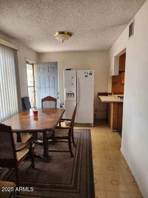 dining area featuring visible vents, a textured ceiling, and light floors