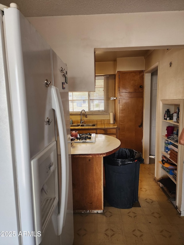 kitchen with brown cabinets, light floors, light countertops, a sink, and white appliances