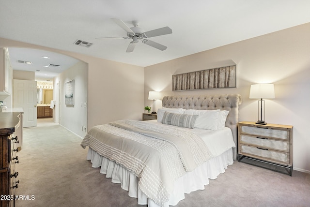 bedroom featuring light carpet, connected bathroom, and ceiling fan