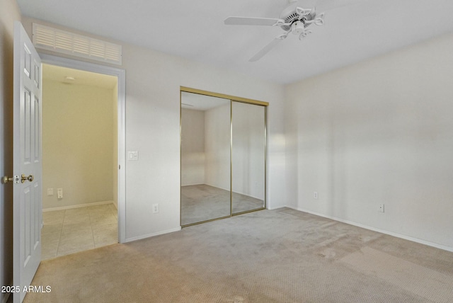 unfurnished bedroom featuring light colored carpet, ceiling fan, and a closet