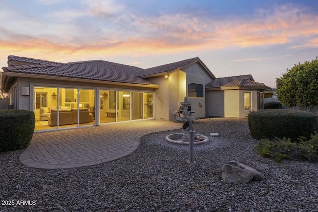 back house at dusk featuring a patio