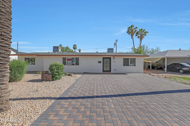 ranch-style home featuring cooling unit and stucco siding